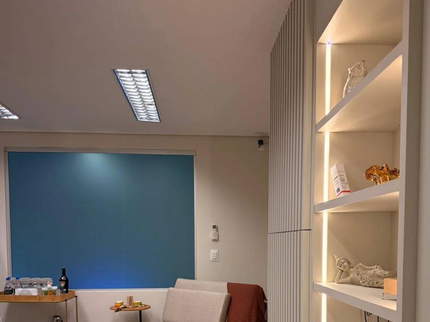 Recepção da clínica, com o sofá e a estante iluminada